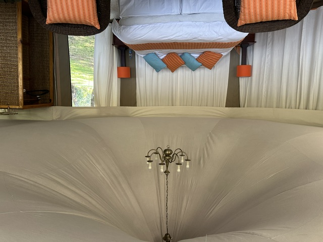 Inside a luxury tent — king bed beneath a chandelier